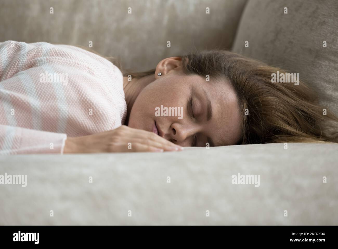Mujer joven cansada durmiendo en casa tumbada en un sofá Foto de stock