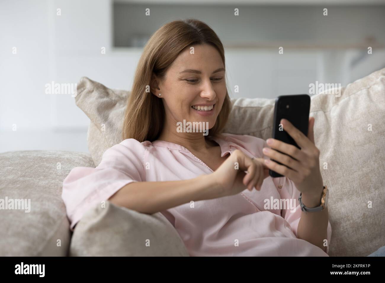 Mujer feliz relajándose en el sofá con un moderno smartphone Foto de stock