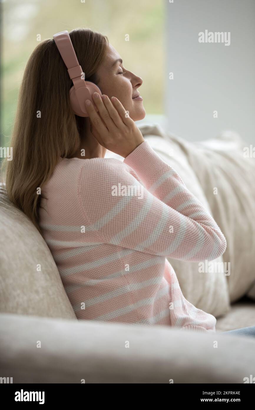 Calme Woman escucha música clásica a través de auriculares inalámbricos, toma vertical Foto de stock