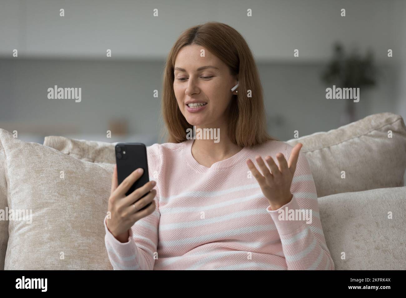 Mujer joven con auriculares que tienen una reunión virtual utiliza la aplicación móvil Foto de stock