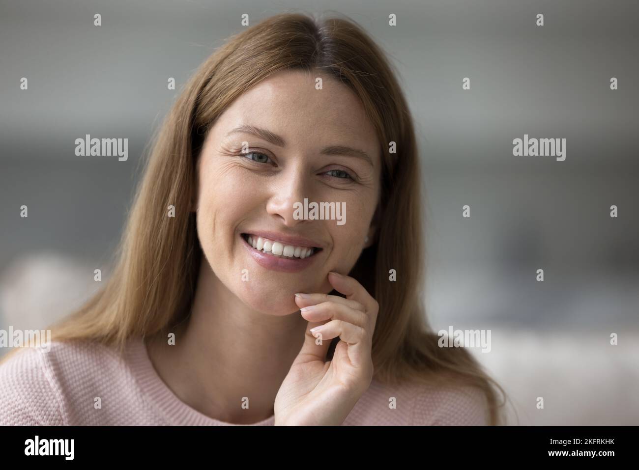Bonita mujer se sienta en el interior sonrisa mirando a un lado, primer plano retrato Foto de stock