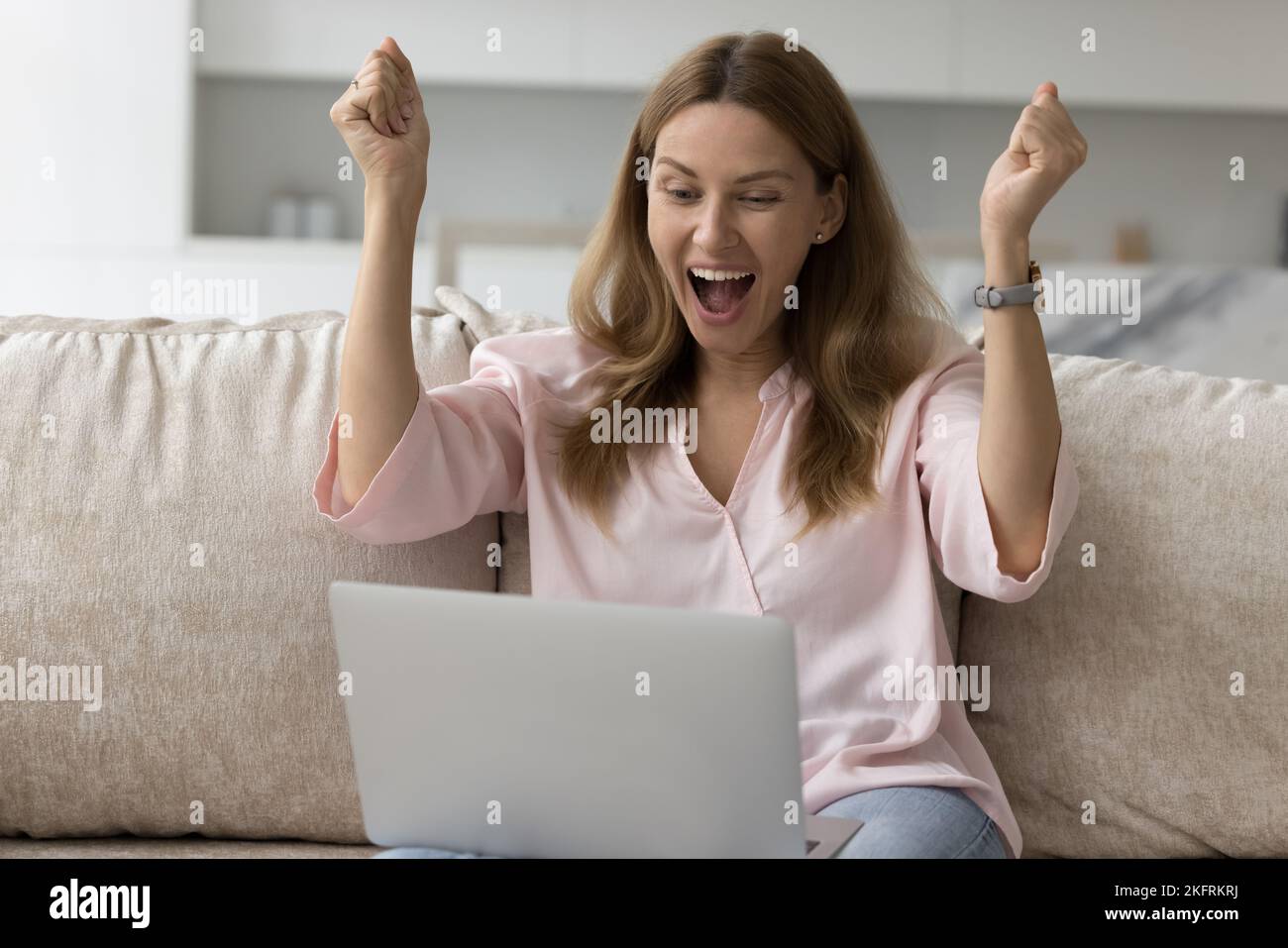 Mujer mira el portátil, grita con alegría celebrar las grandes noticias Foto de stock