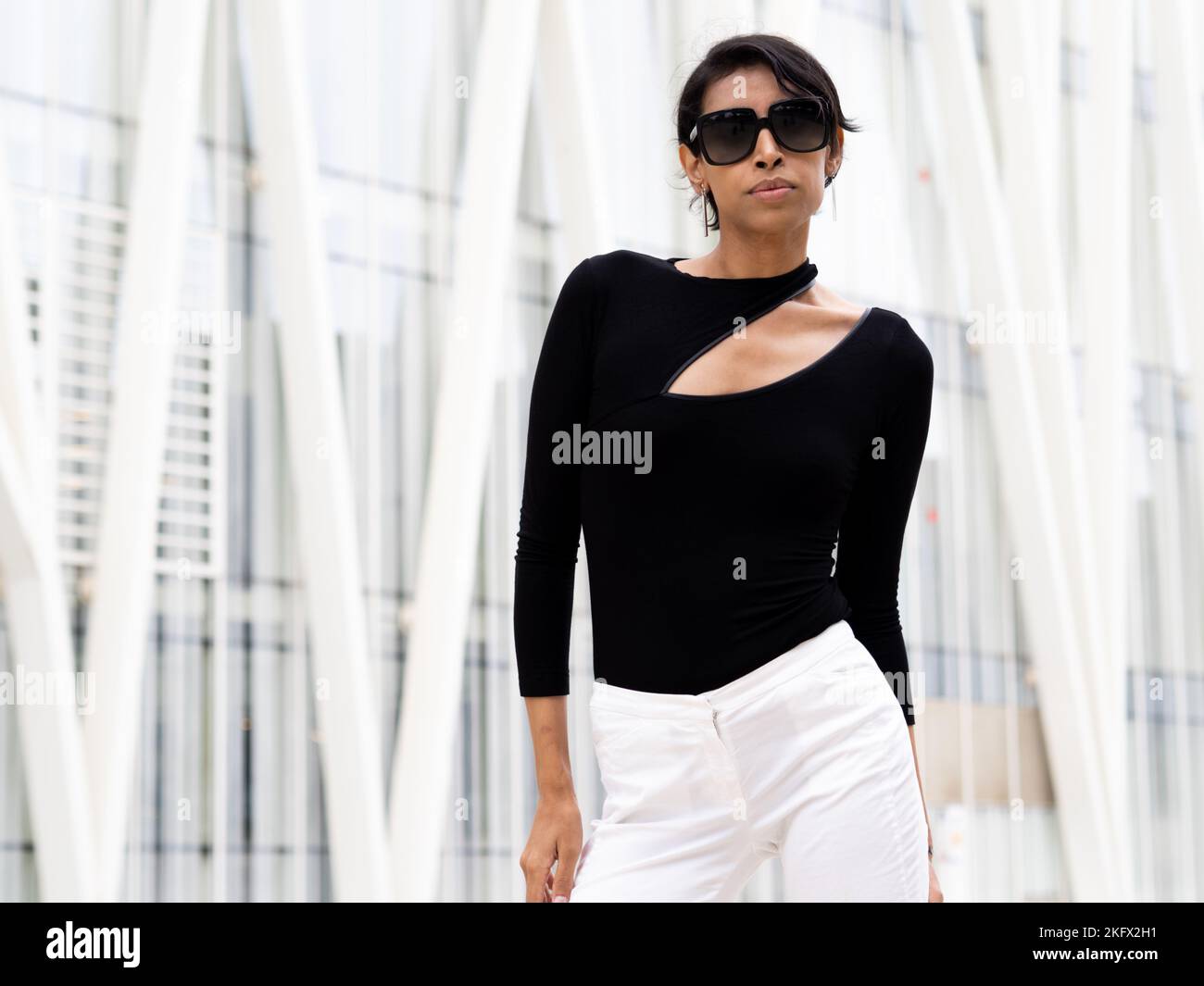 Mujer transexual de moda posando en una ciudad mirando la cámara con gafas de sol Foto de stock