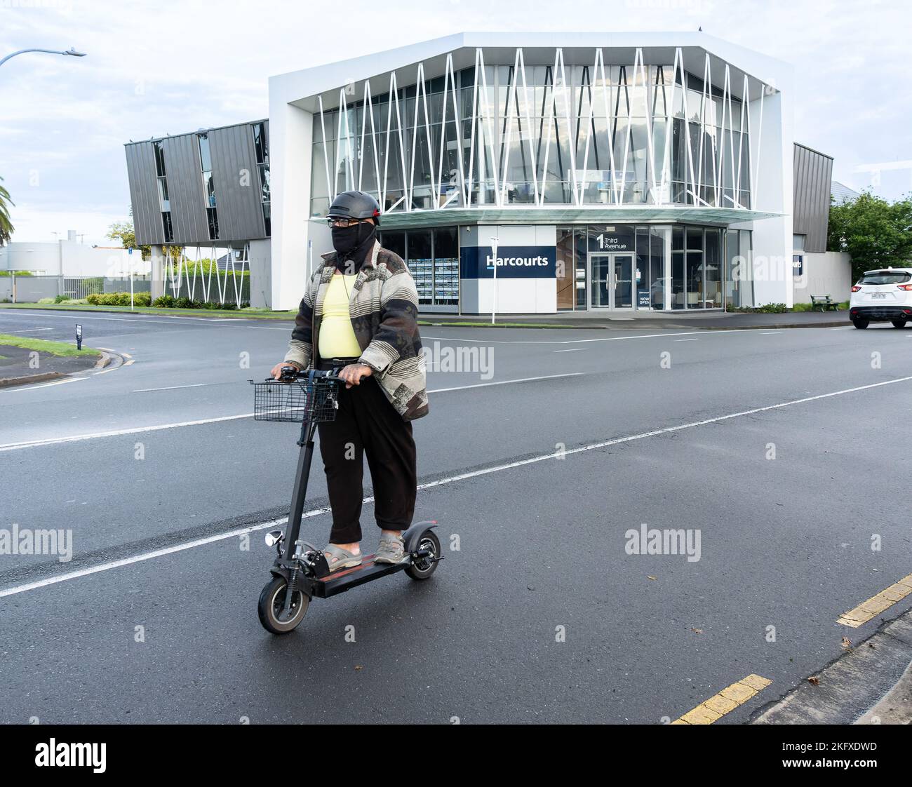 Tauranga Nueva Zelanda - 18 2022 de noviembre; hombre enmascarado en scooter montando en la calle de la ciudad por la mañana. Foto de stock