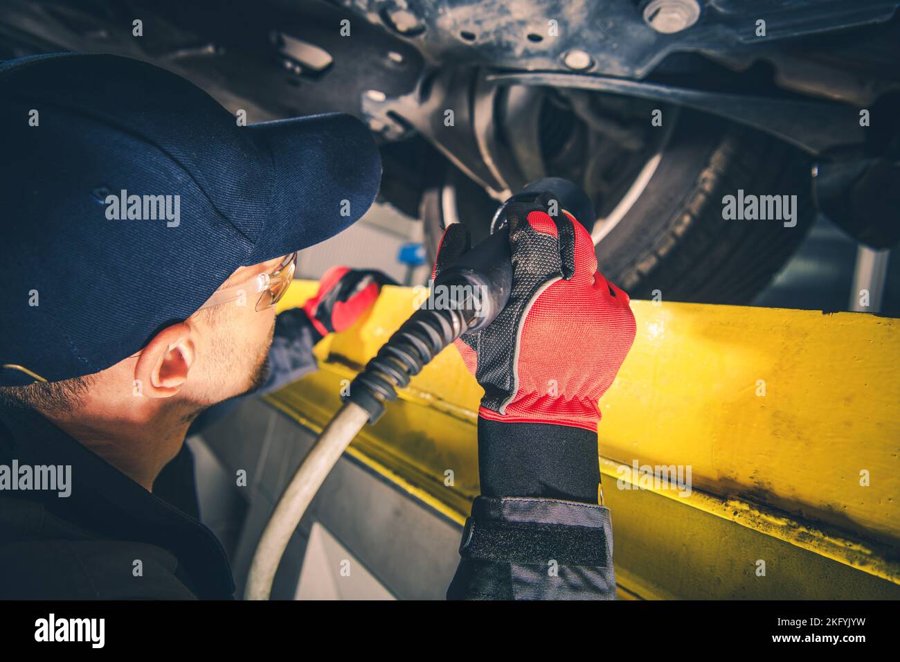 Mecánico Profesional Revisión del tren de rodaje del vehículo usando una linterna durante la inspección programada del automóvil. Tema de mantenimiento de automóviles. Foto de stock