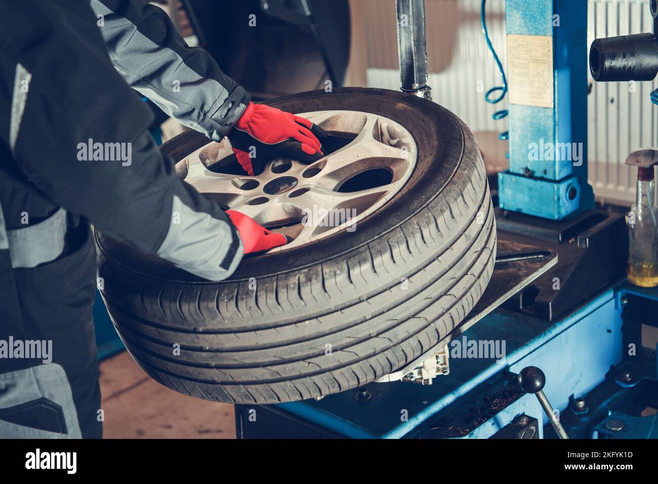 Mecánico profesional que sostiene la rueda del coche en sus manos listo para cambiar neumático. Tema de mantenimiento de vehículos de temporada. Foto de stock