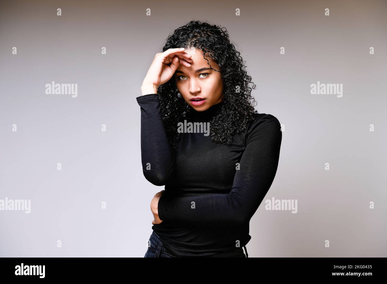 Mujer joven con la mano en la frente mirando intensamente | Fondo blanco con espacio de copia Foto de stock