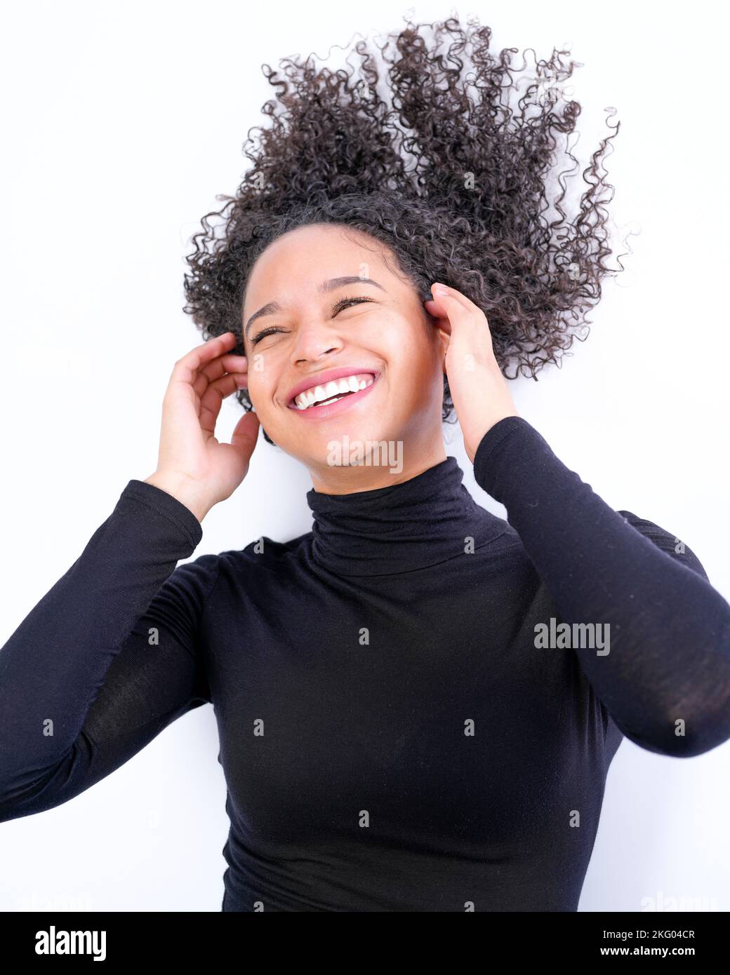 Joven mujer multirracial puesta sobre fondo blanco riendo | Felicidad Foto de stock