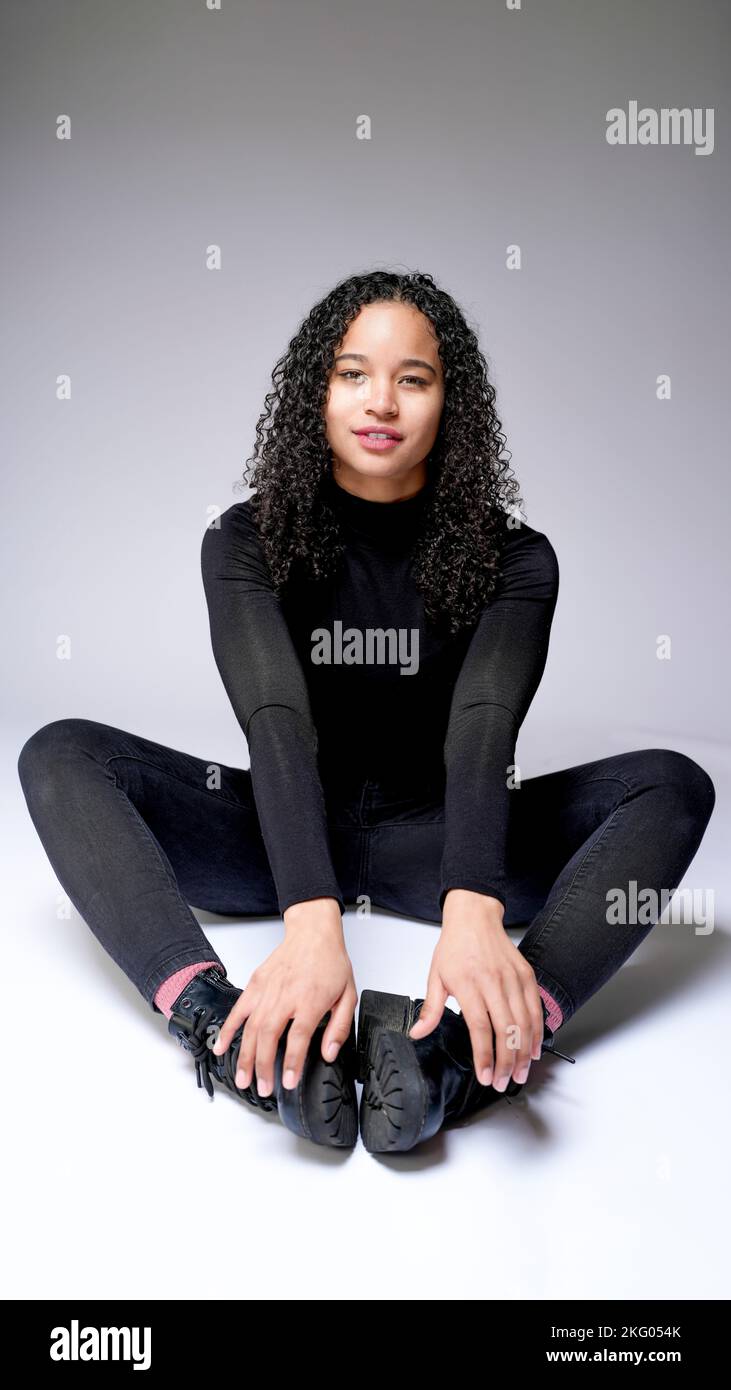 Joven mujer multirracial sentada en Cobblers pose sonriendo | Fondo blanco con espacio de copia Foto de stock