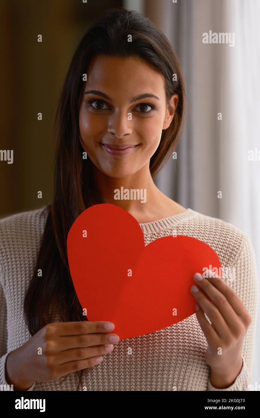 Mujer, cara y corazón rojo papel en casa o en casa para el día de San Valentín, cardiología cirugía donante de órganos o apoyo. Retrato, sonrisa o persona india feliz Foto de stock