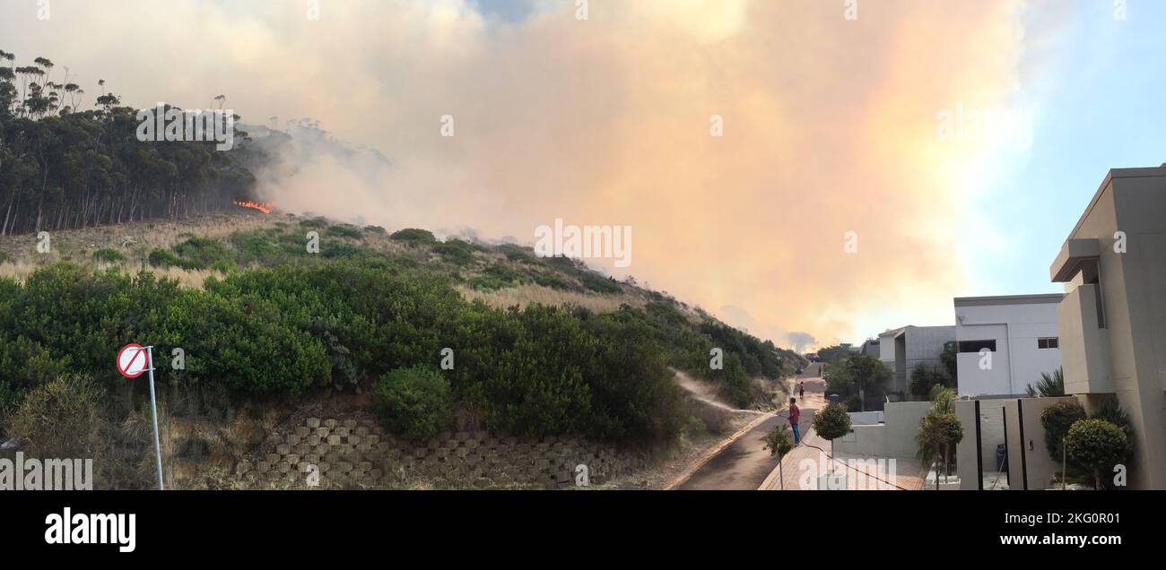 Un incendio salvaje acercándose a un barrio residencial. Foto de stock