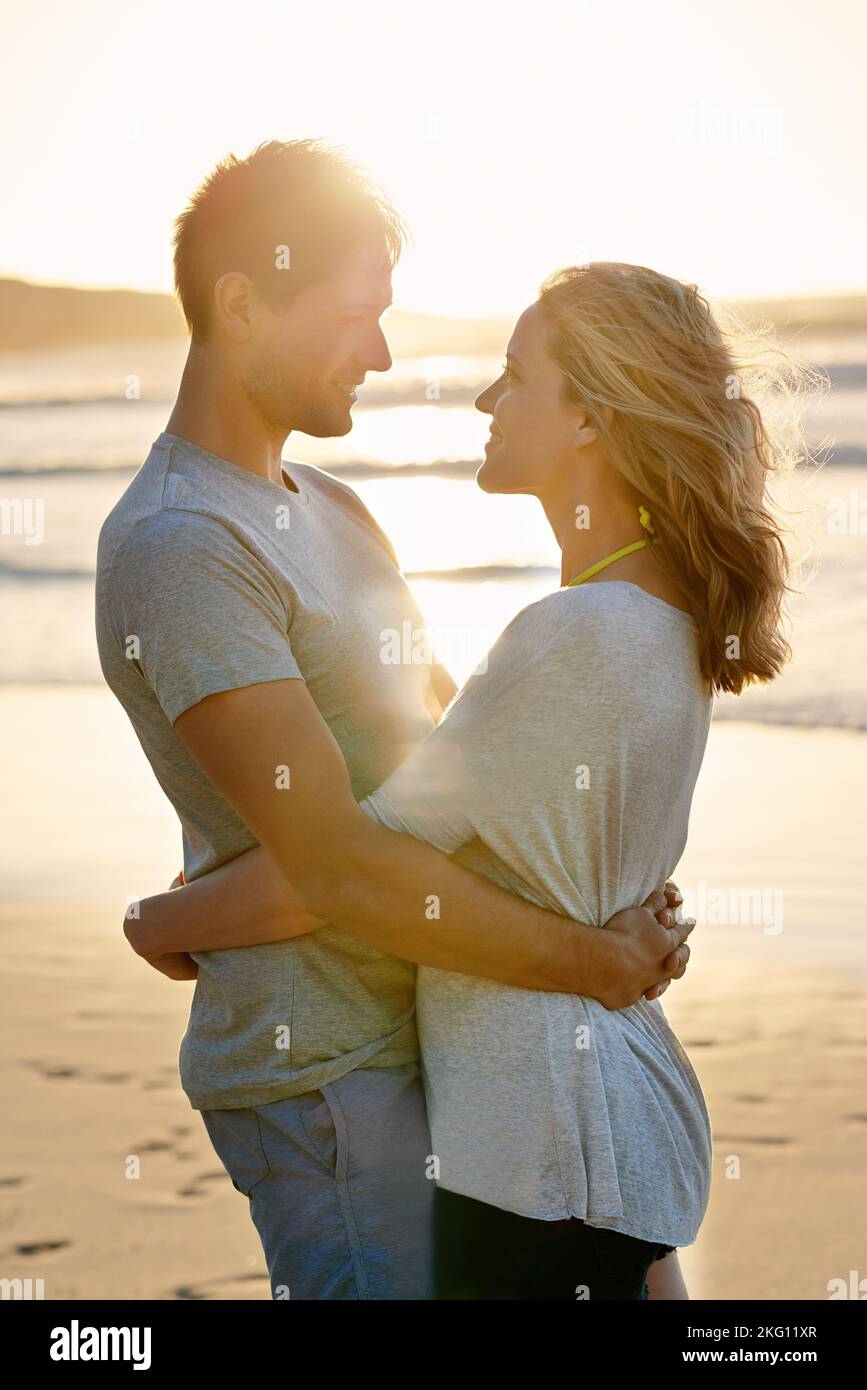 Agárgueme bien y nunca deje ir. Una pareja se sostiene alrededor de la cintura en la playa. Foto de stock