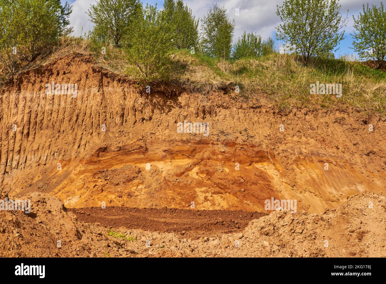 La capa superior de tierra excavada por el cucharón excavador para la extracción de arena en una cantera Foto de stock