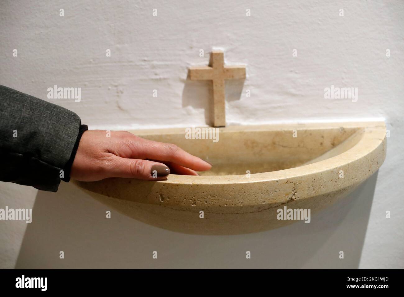 Monatna estación de Iglesia. Mano de una mujer y fuente de agua santa. Suiza. Foto de stock