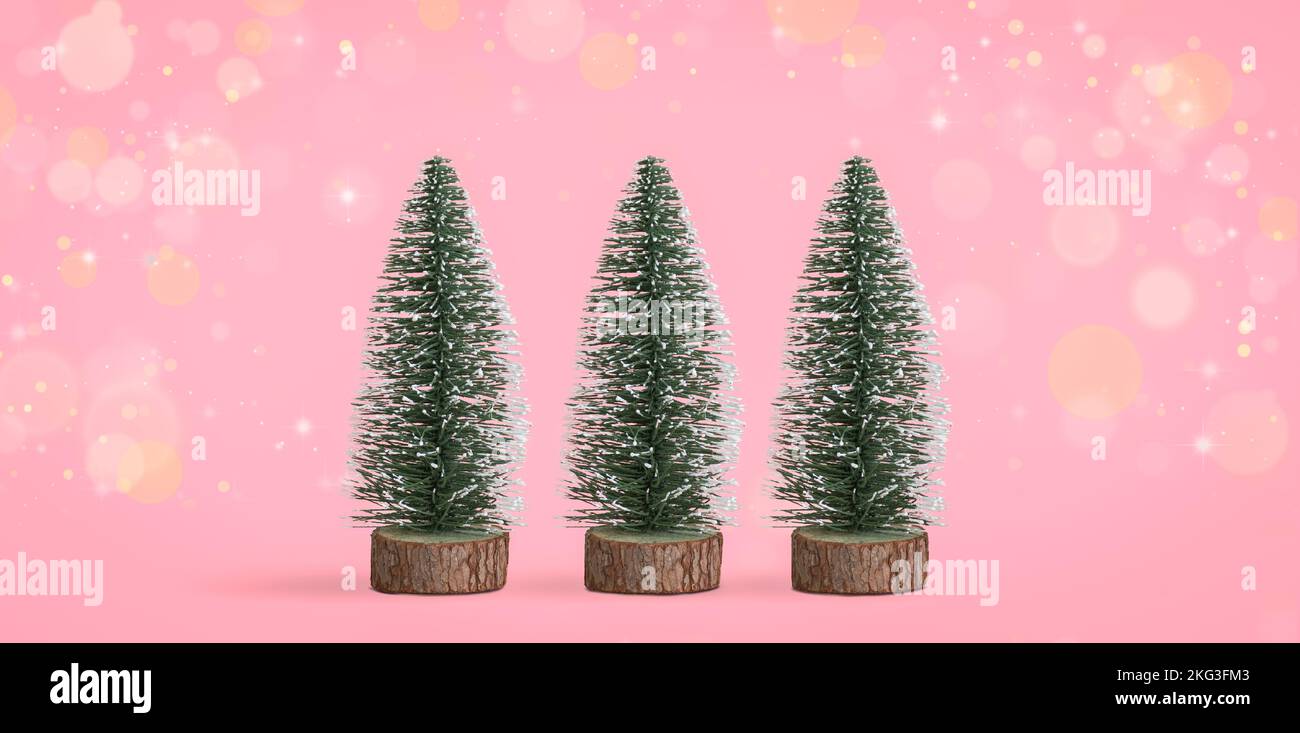 Mini árboles de Navidad decorativos sobre fondo de bokeh rosa. Foto de stock