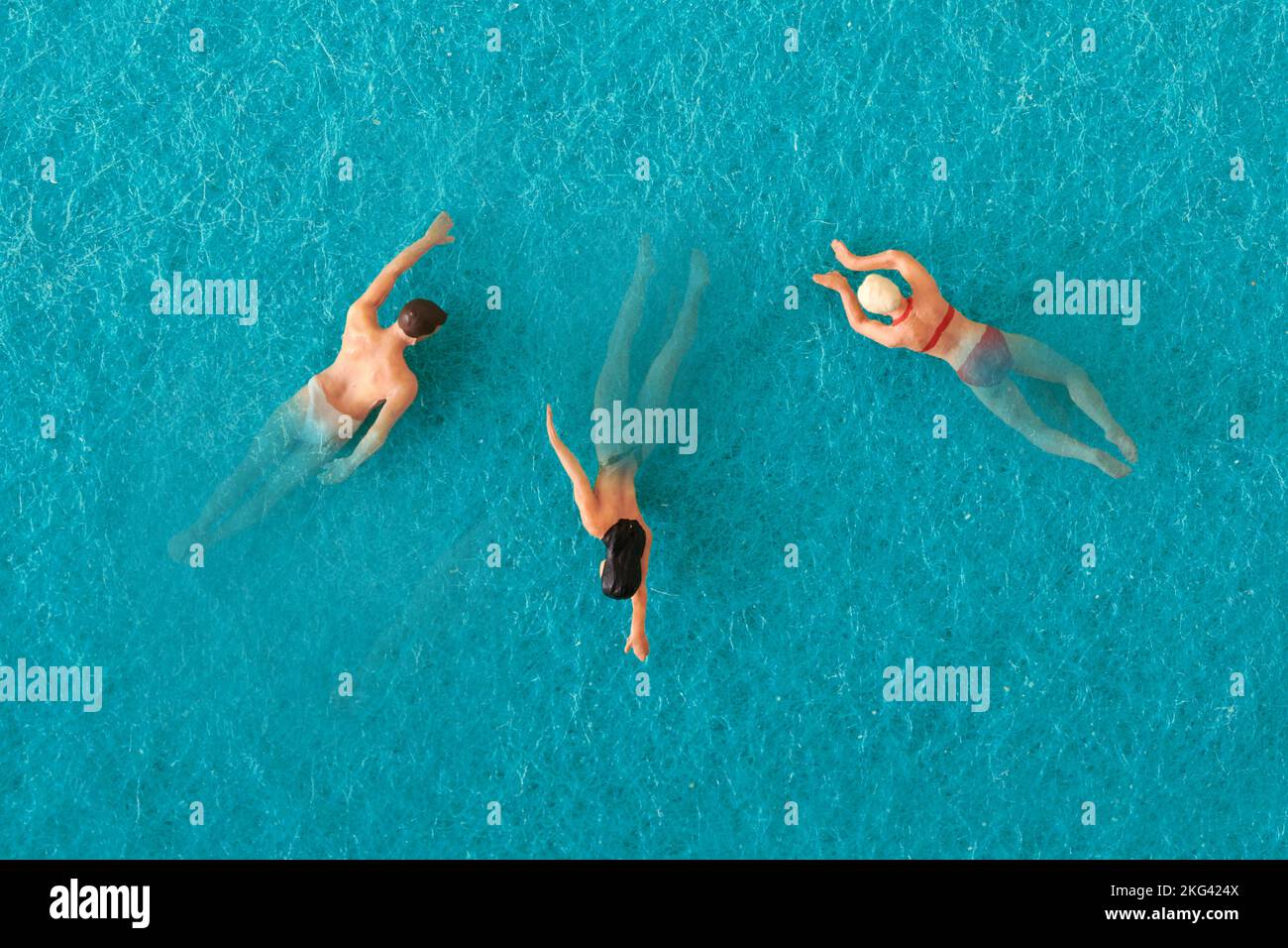 Vista superior de hombre de juguete y mujeres nadando en agua azul de la piscina Foto de stock