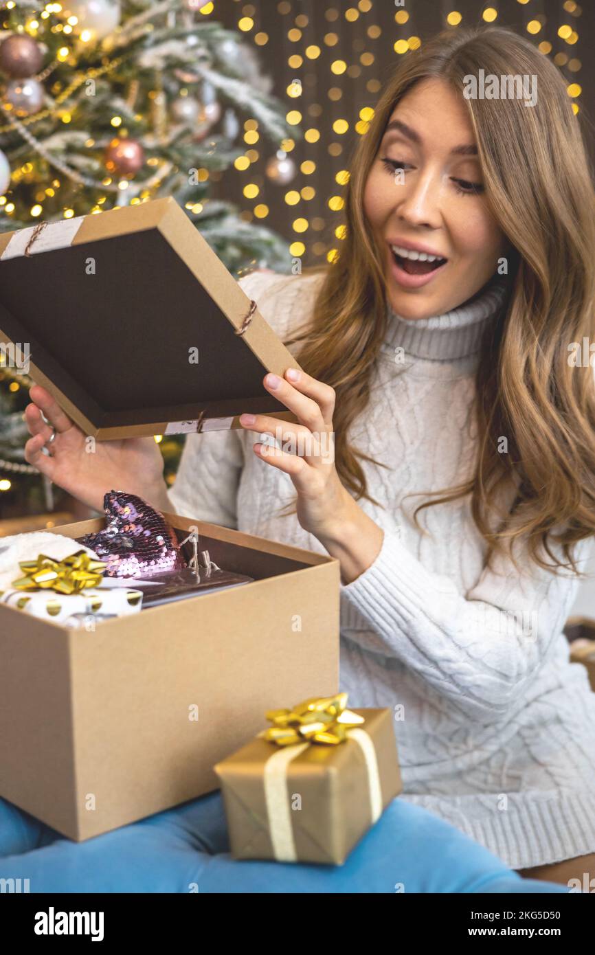 Mujer de asombro abrir caja de regalo deseado artesanía presente celebrar  vacaciones de invierno en el árbol de Navidad Fotografía de stock - Alamy