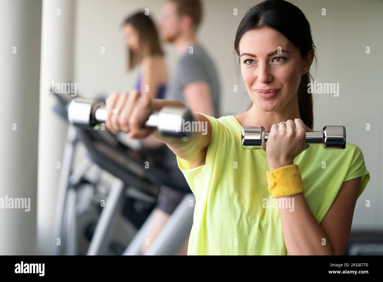 Atractiva mujer joven trabajando con pesas en el gimnasio. Foto de stock