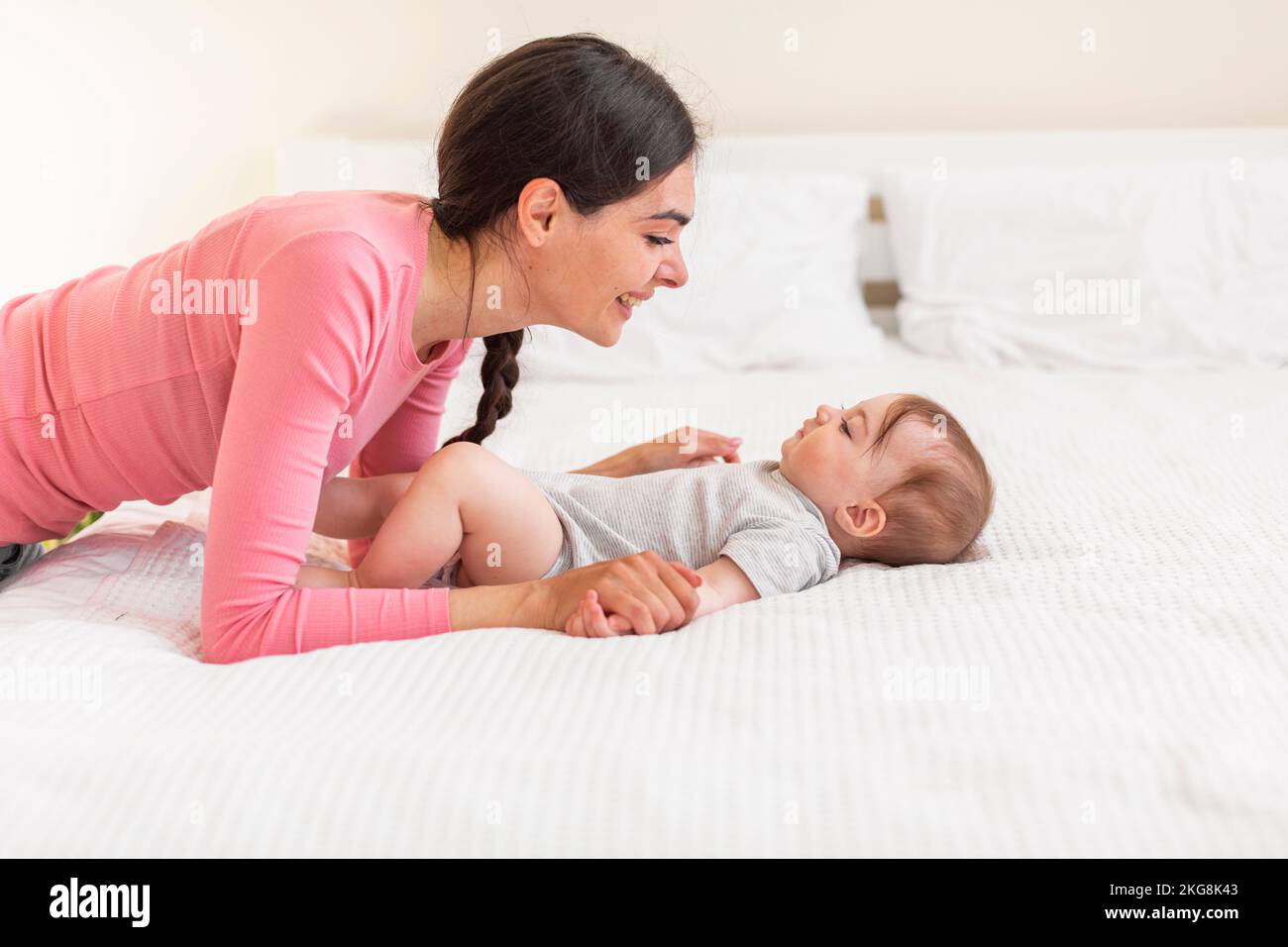 Conexión madre-hijo. Amorosa vinculación de mamá con su adorable recién nacido en casa, relajándose en la cama juntos Foto de stock