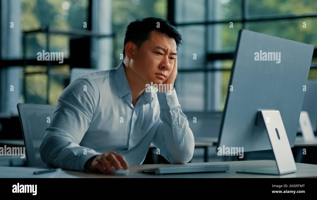Aburrido trabajador asiático perezoso hombre coreano japonés agotado hombre cansado sentarse en la oficina dormido cansado de aburrido trabajo en línea en el ordenador desarrollar Foto de stock