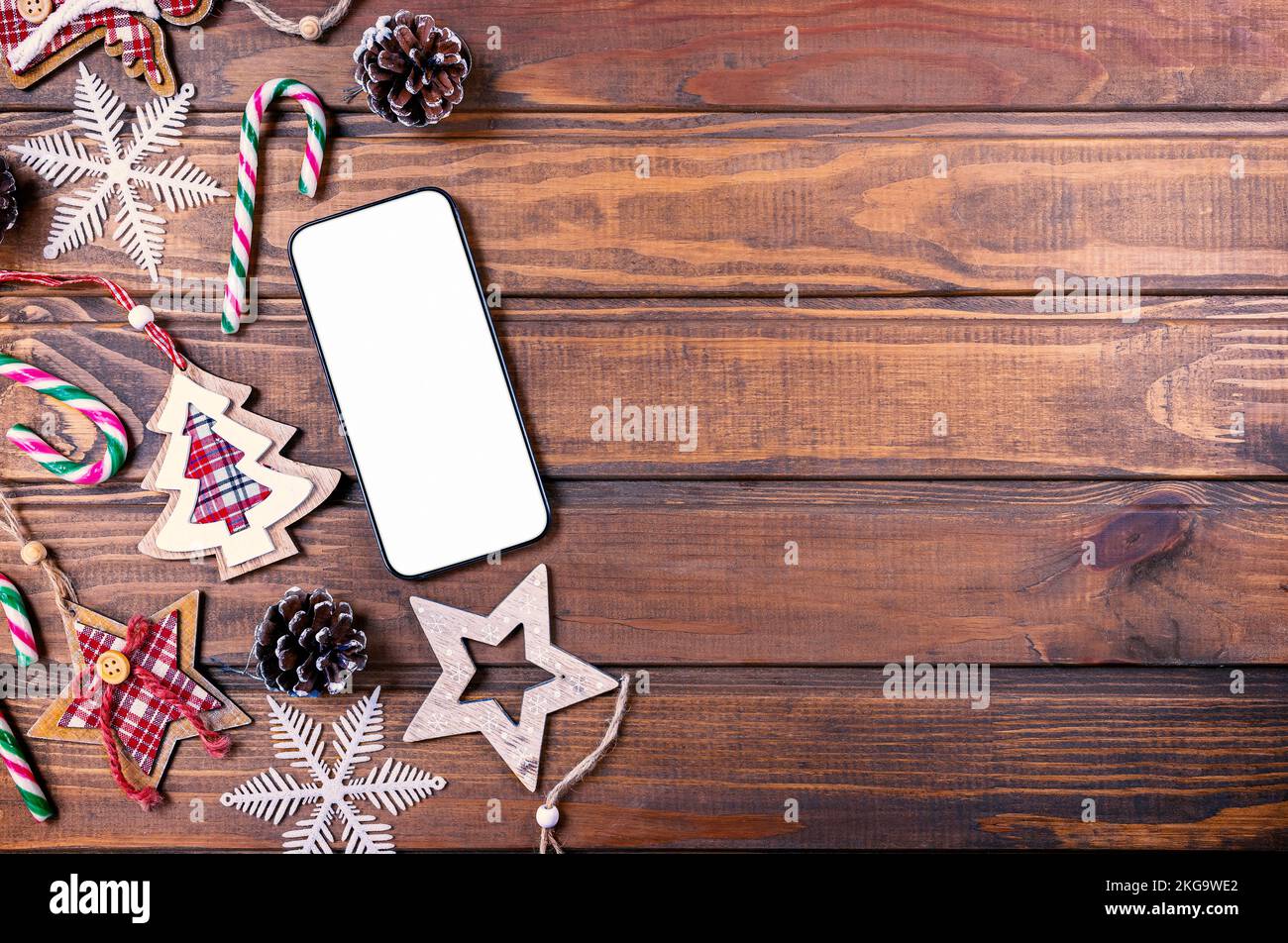 Maqueta de smartphone con adornos navideños rústicos para la presentación de la aplicación. Vista desde arriba Foto de stock