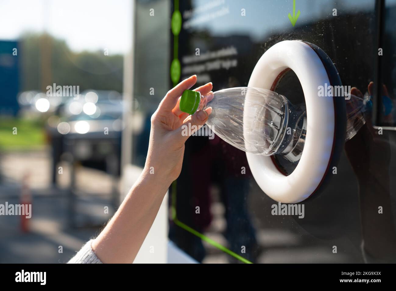 Una mujer utiliza una máquina de autoservicio para recibir botellas y latas de plástico usadas en la calle de una ciudad Foto de stock