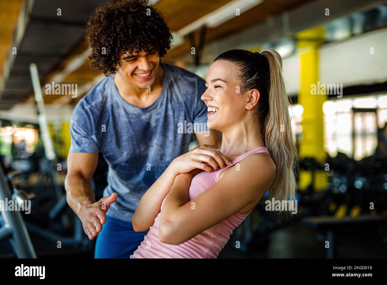 Hermosa mujer haciendo ejercicios en el gimnasio con entrenador personal juntos. Deporte, concepto de personas Foto de stock