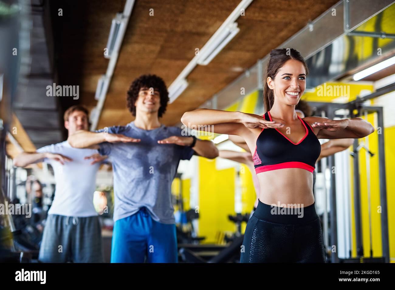 Grupo de jóvenes, amigos sonriendo y disfrutar del deporte en el gimnasio. La gente ejercita, trabaja el concepto. Foto de stock