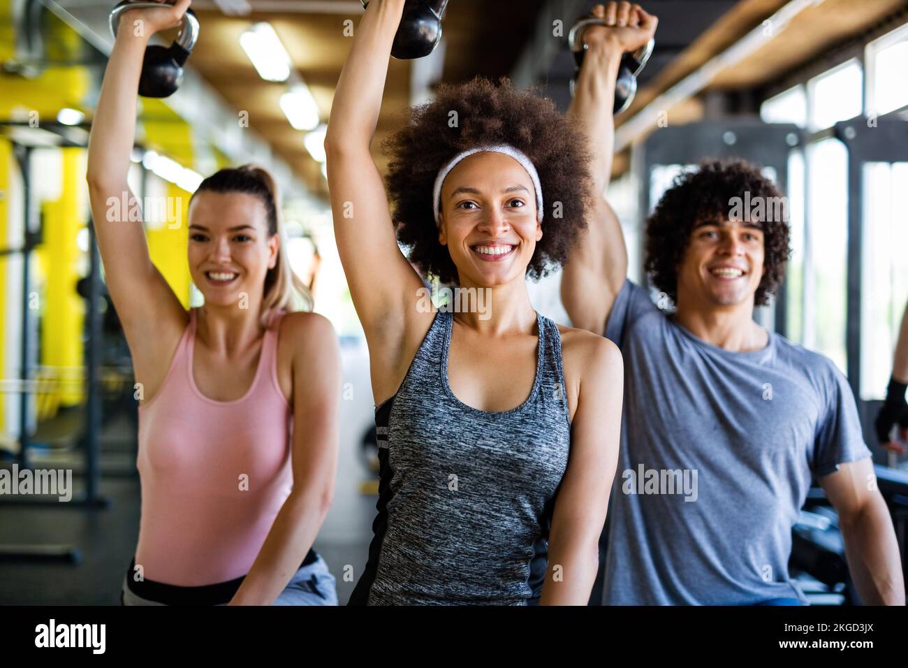 Grupo de personas en forma levantando pesas durante una clase de ejercicio en el gimnasio Foto de stock