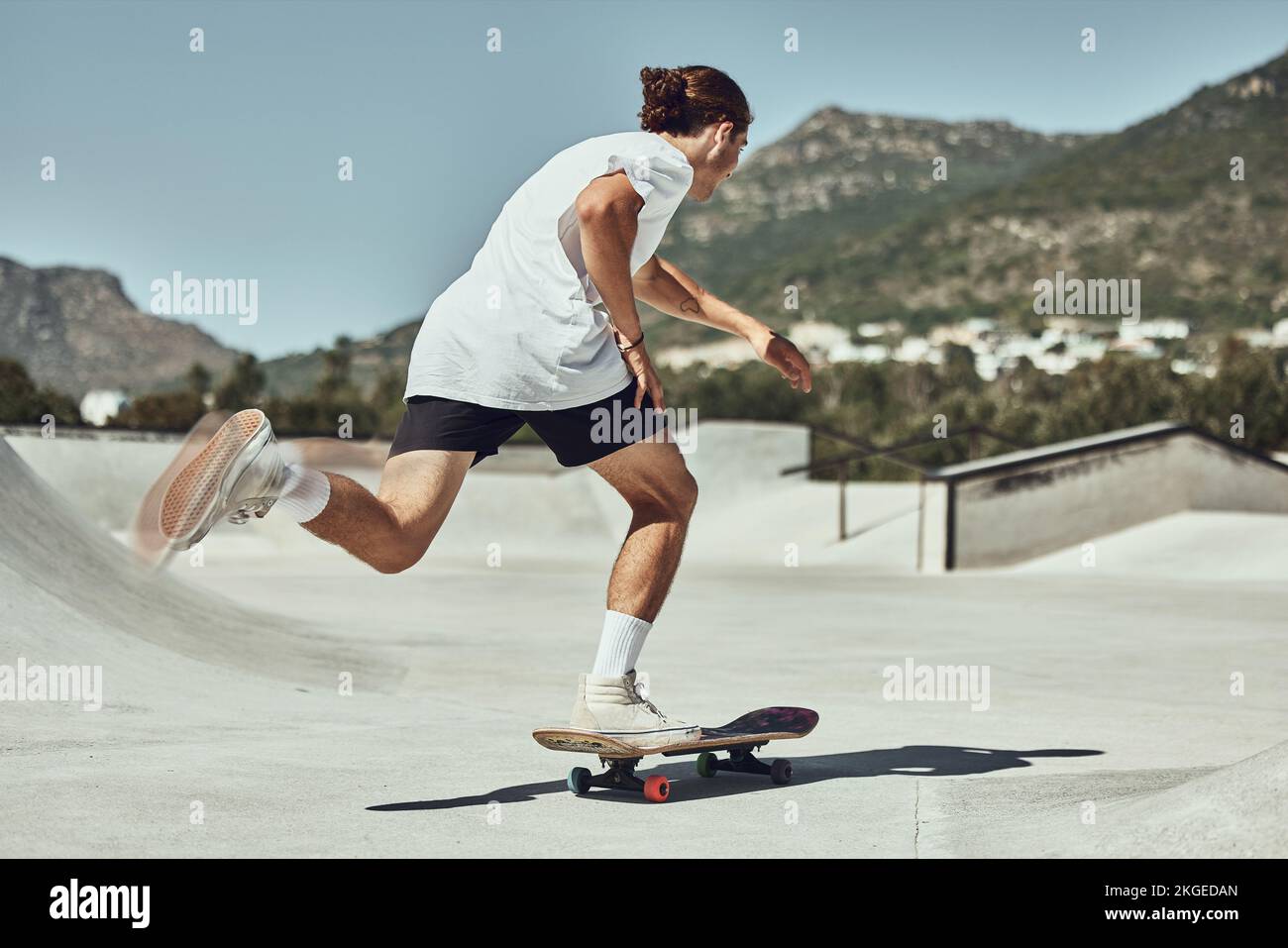 Patinaje, hombre joven y skateboard en skate park en ciudad urbana, fitness o entrenamiento para afición de moda. Juventud, patinadora y actividad física en concreto Foto de stock