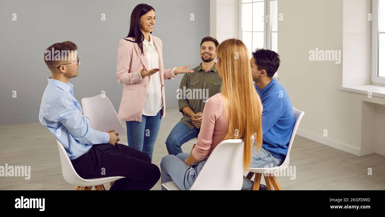 Una mujer sonriente habla con los empleados en una reunión informal Foto de stock