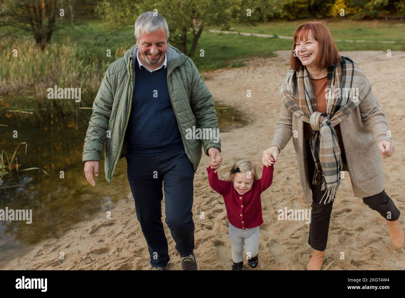 Abuelos caminando sobre la arena con su nieta Foto de stock