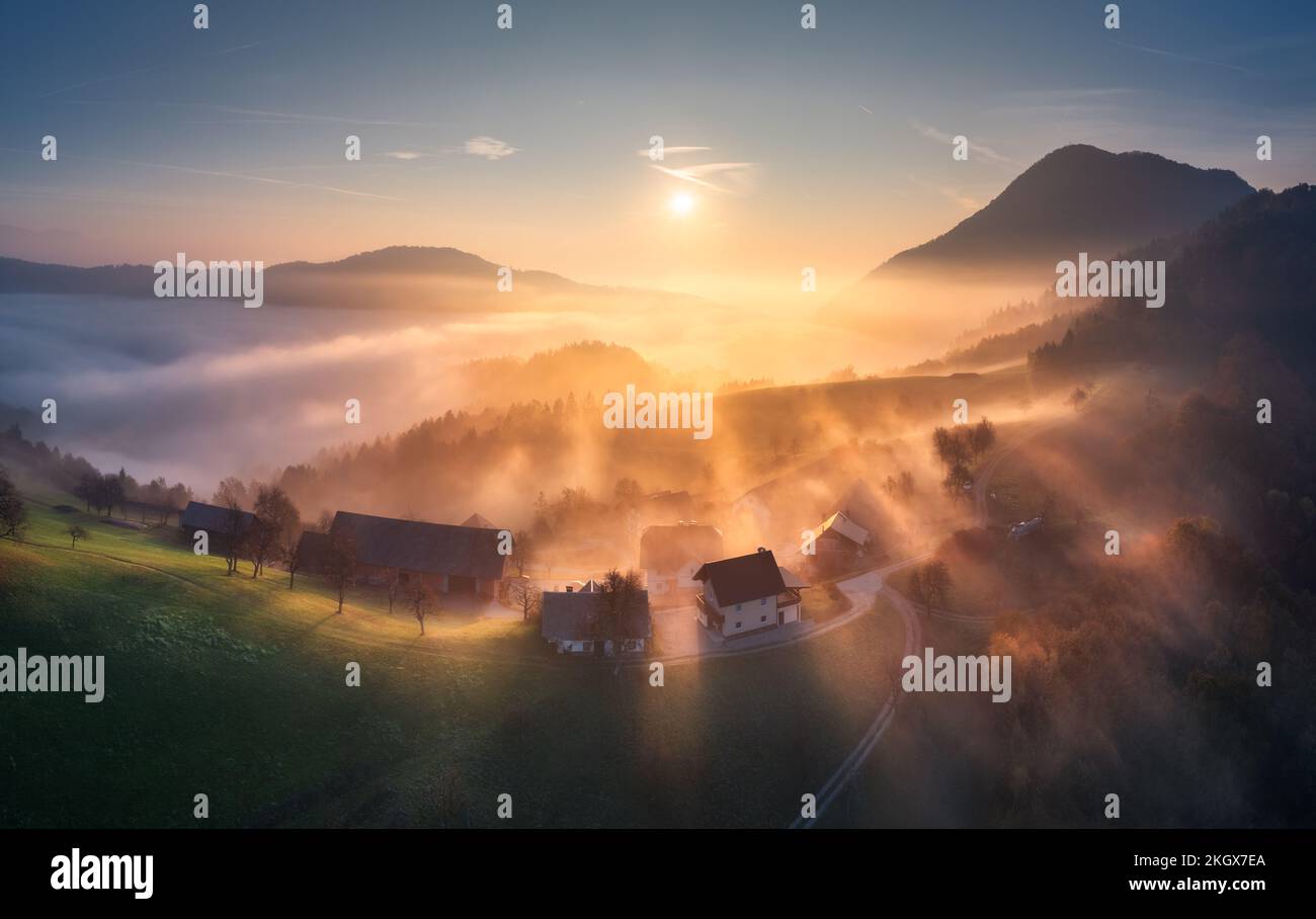 Vista aérea del pueblo de montaña en nubes anaranjadas al amanecer Foto de stock