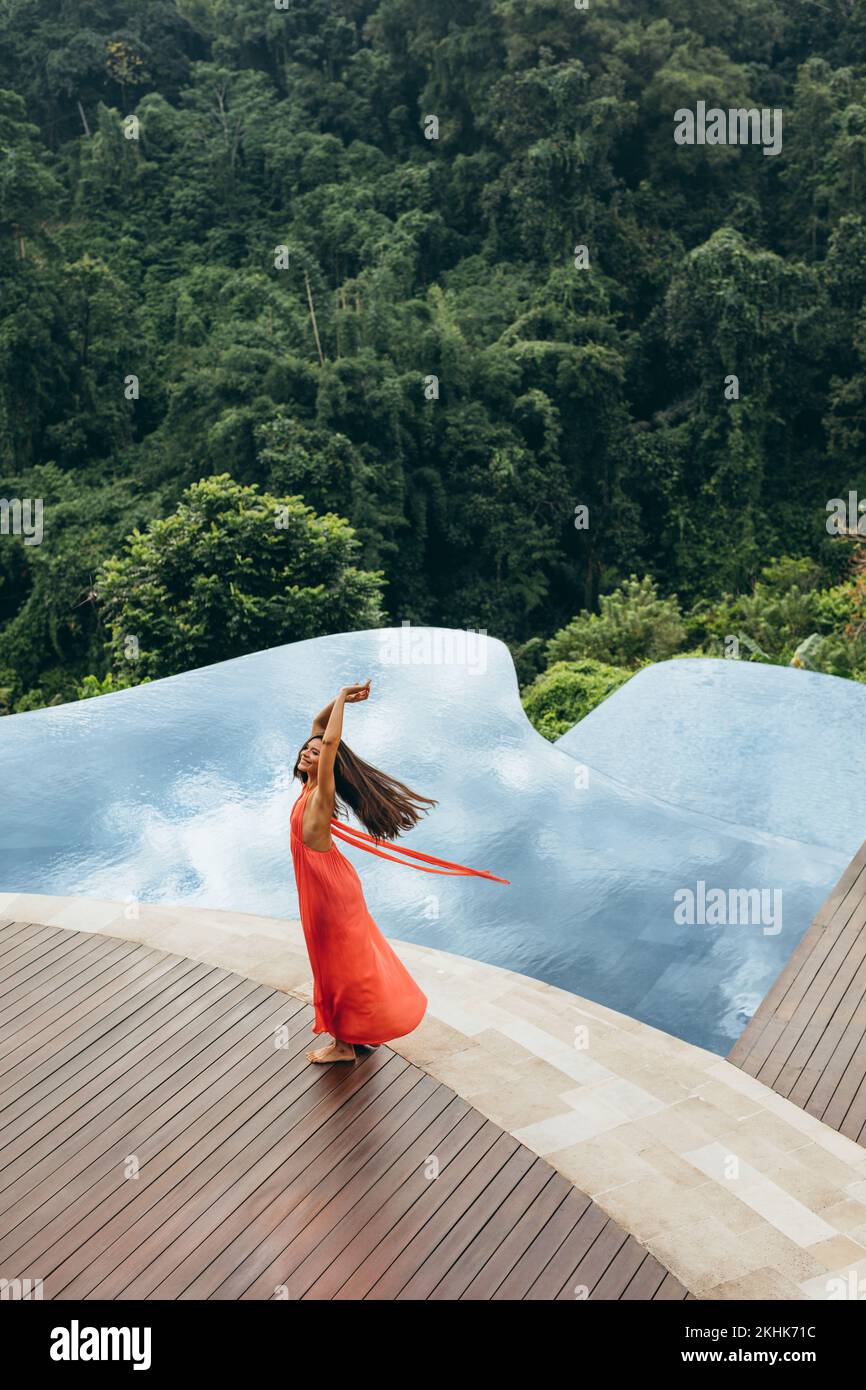 Foto aérea atractiva joven disfrutando de sus vacaciones en un complejo de lujo. Modelo femenino junto a la piscina con aspecto feliz. Foto de stock
