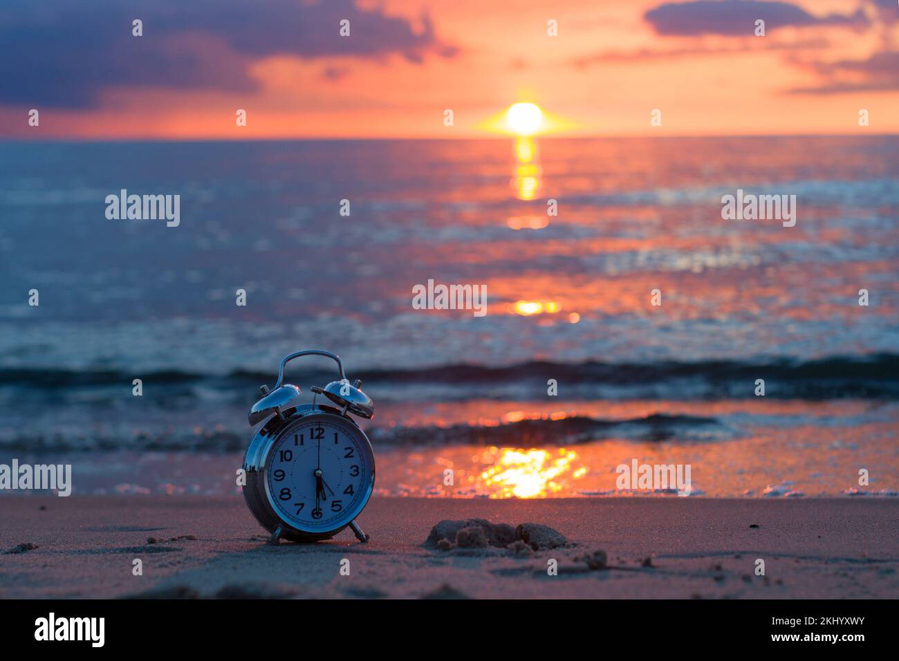 Reloj despertador vintage con puesta de sol en la playa Foto de stock