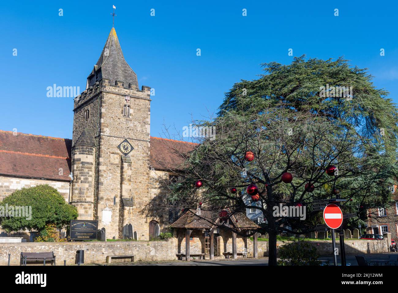 St Mary Magdalene & St Denys Church en Midhurst, West Sussex, Inglaterra, Reino Unido, con un árbol en la plaza del mercado decorado con bolas rojas para Navidad Foto de stock