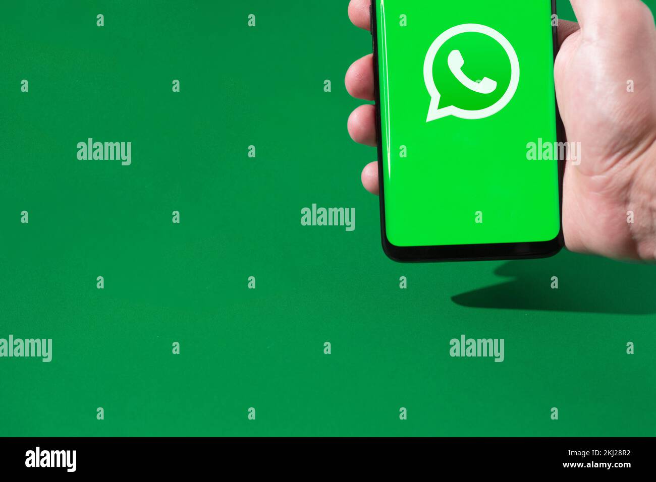 Persona que sostiene un smartphone con el logotipo de WhatsApp en la pantalla. Foto de stock