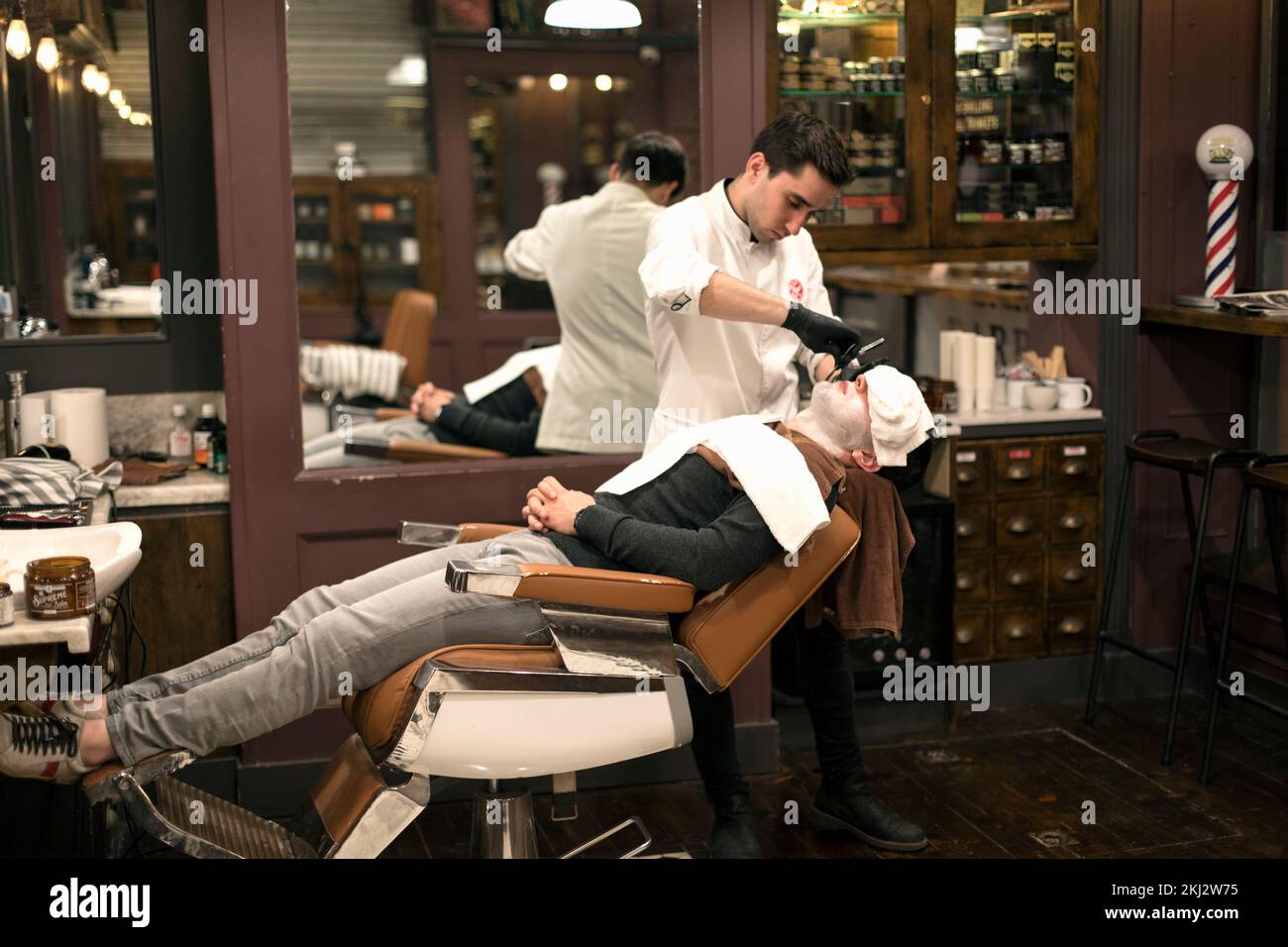 Irlanda,Dublín, barbero Dar un afeitado de afeitar recto a un cliente Foto de stock