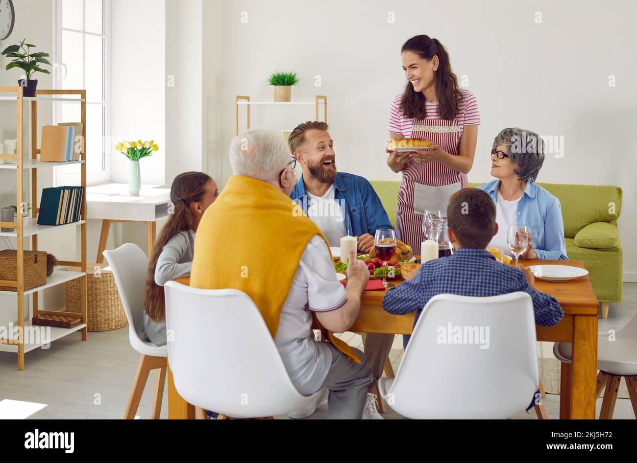 La feliz familia multi-generacional está celebrando el agradecimiento en una mesa festiva con deliciosa comida. Foto de stock