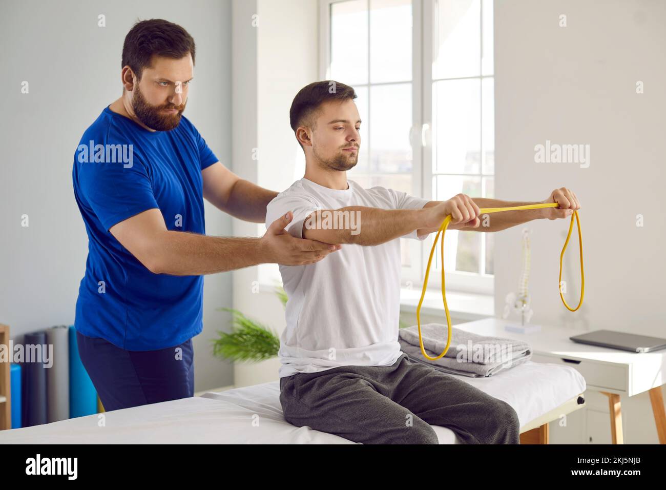 Paciente fisioterapeuta haciendo ejercicios de rehabilitación física con banda de resistencia Foto de stock