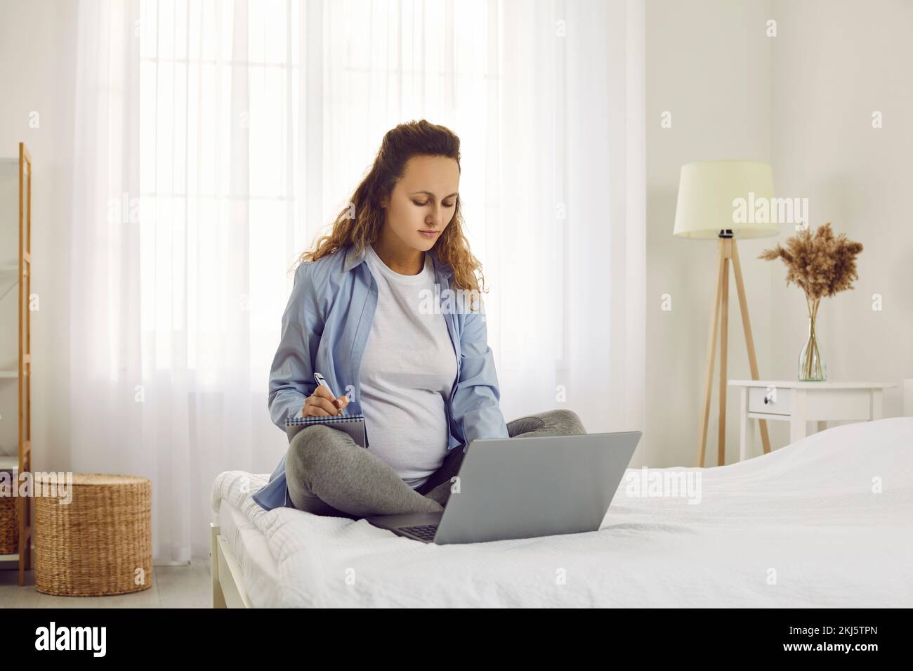 Mujer embarazada sana trabajo en línea en la computadora Foto de stock