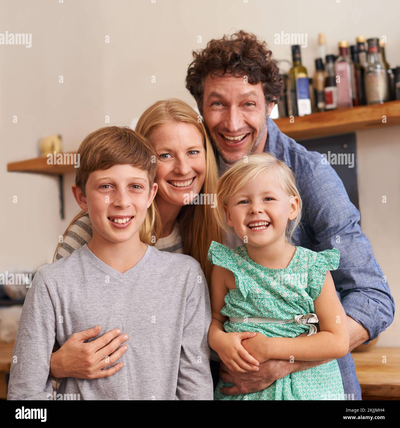 Una familia feliz y cariñosa. Un retrato recortado de una familia feliz de pie en su cocina en casa. Foto de stock