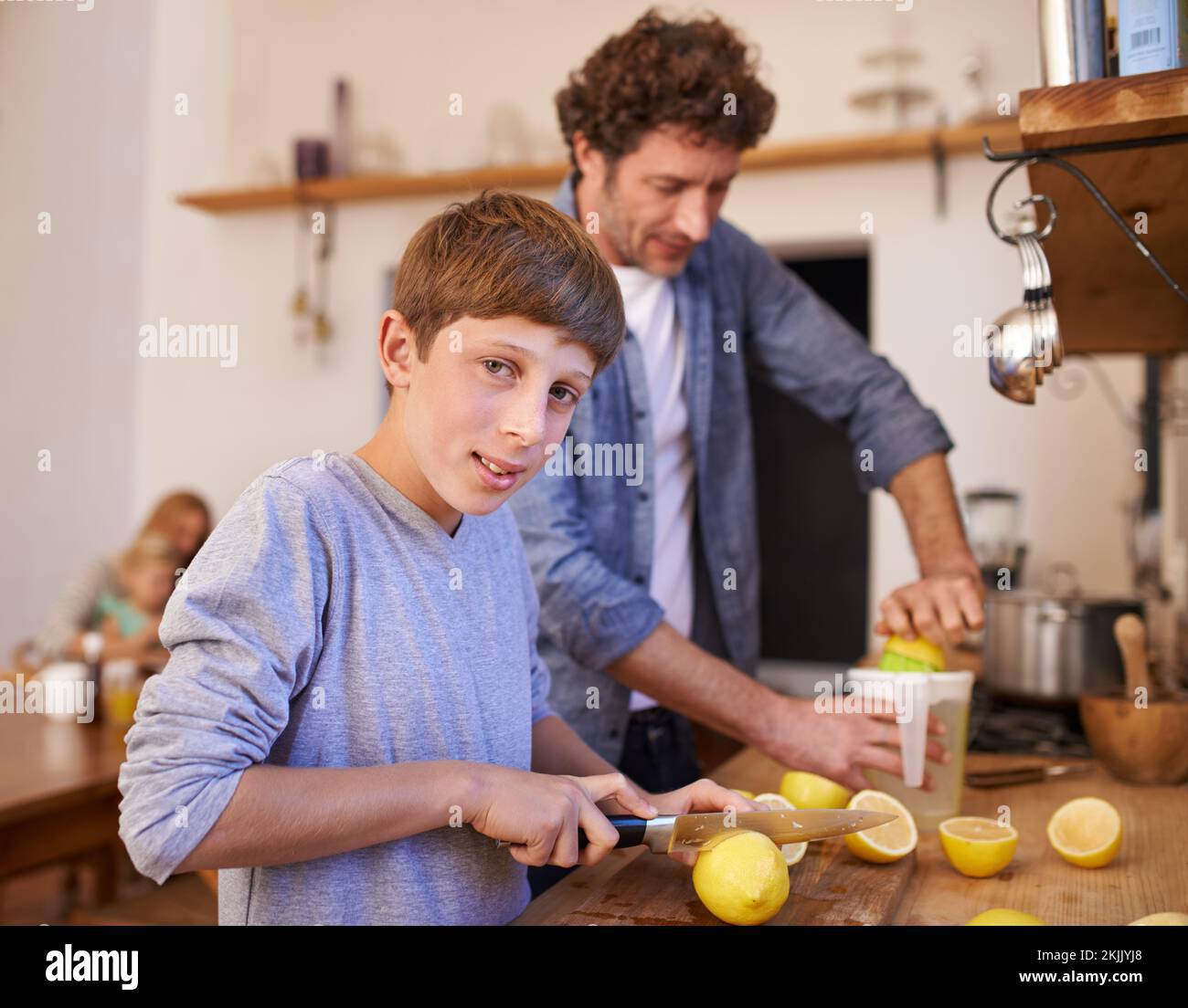 Hacemos la mejor limonada. Un retrato recortado de un niño feliz haciendo limonada con su padre en la cocina. Foto de stock