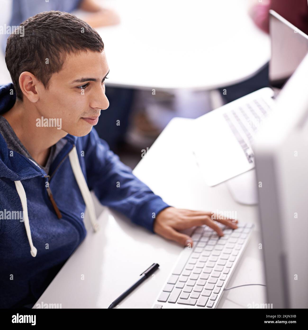 Dedicado a la fecha límite. un joven que trabaja en su ordenador en una oficina. Foto de stock