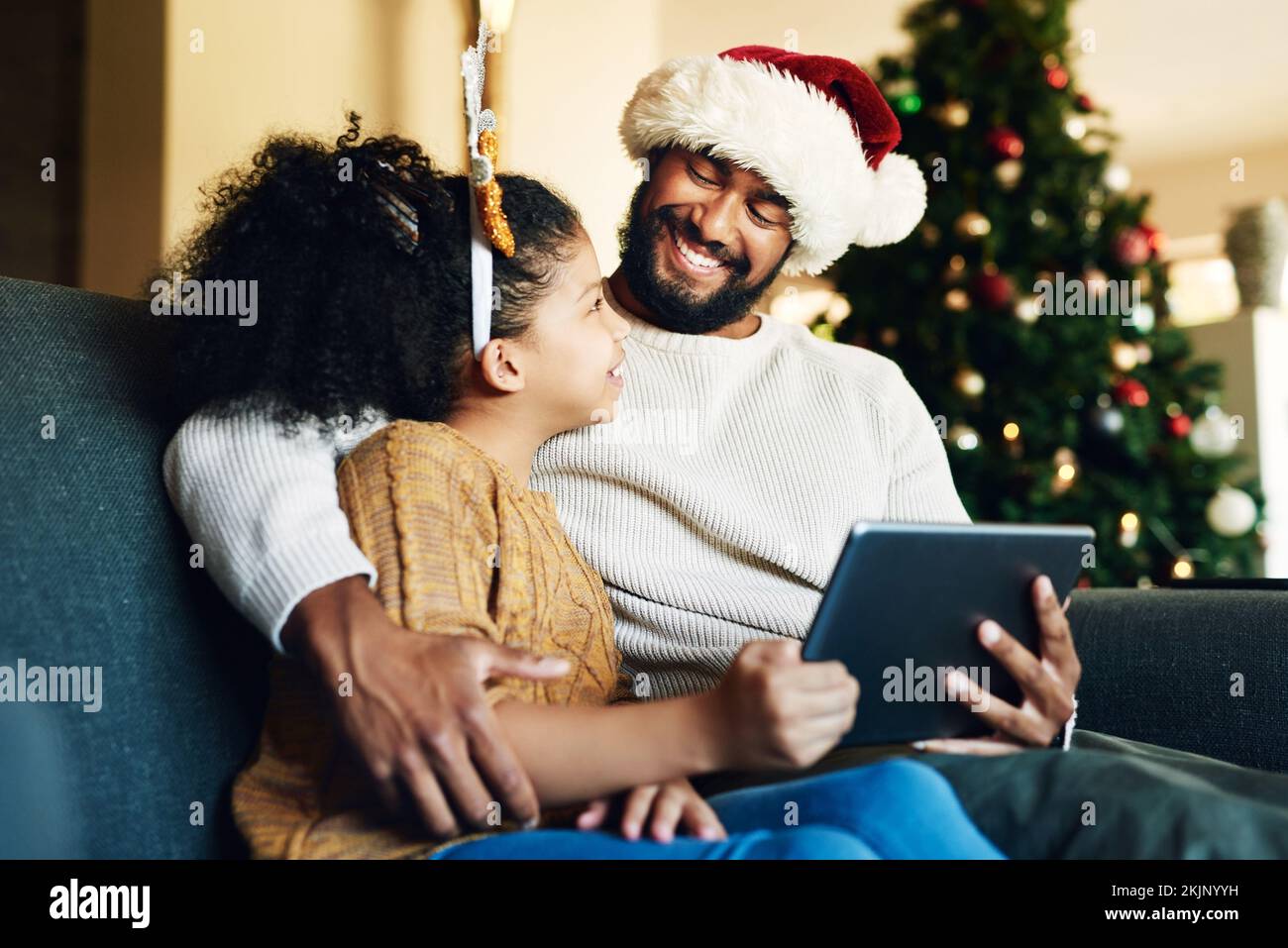 Navidad, familia y tableta digital para ver películas en directo, juegos divertidos o redes sociales en el sofá del salón de la casa. Feliz sonrisa madre, padre y niña Foto de stock