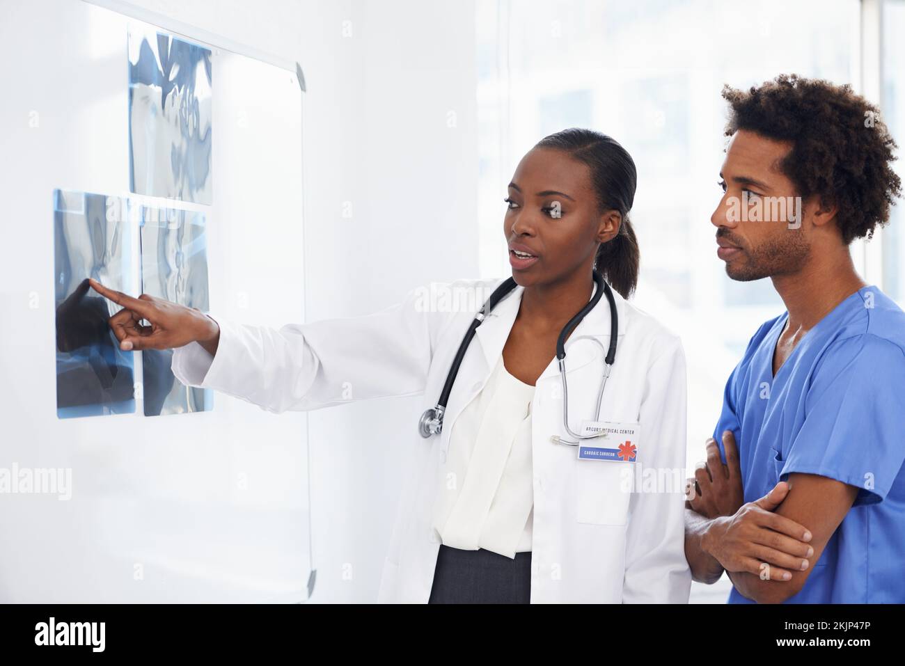 Es genial en explicar los rayos X. Médico afroamericano y enfermera masculina que estudian rayos X. Foto de stock
