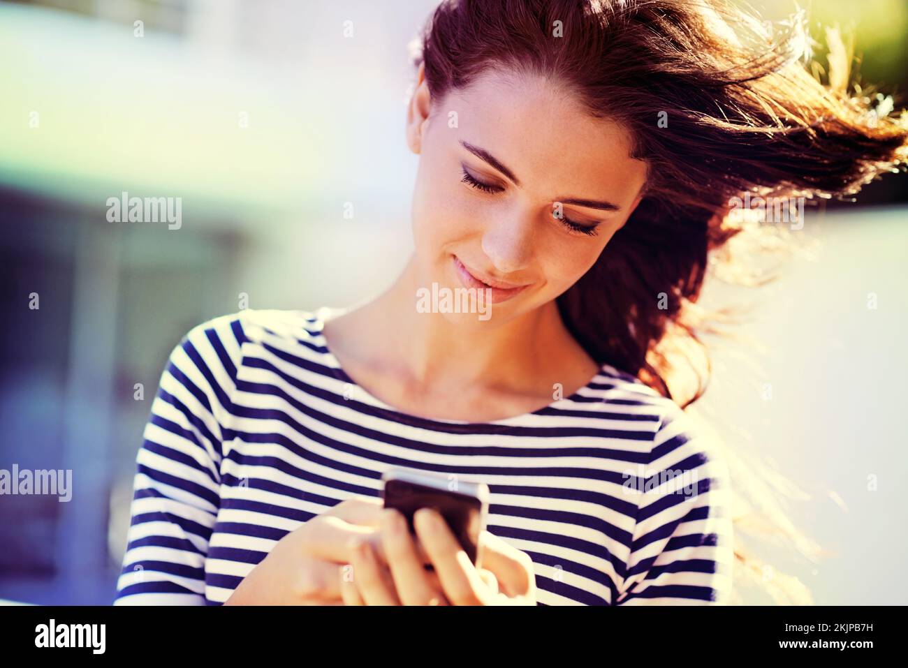 Shes siempre accesible. una hermosa mujer joven usando un teléfono móvil al aire libre. Foto de stock