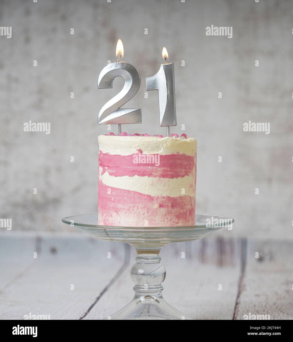 21st pastel de cumpleaños pastel rosa y plata con algo de rociado y 21st  luz de velas sobre un fondo blanco de madera Fotografía de stock - Alamy