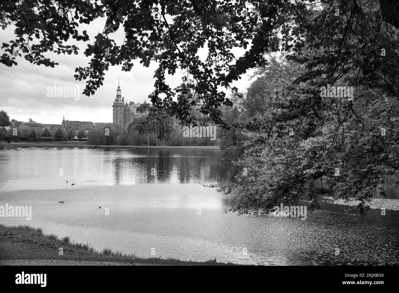 Parque del castillo de Frederiksborg en blanco y negro, con el lago creado, en el fondo el castillo. Caminar en Dinamarca Foto de stock