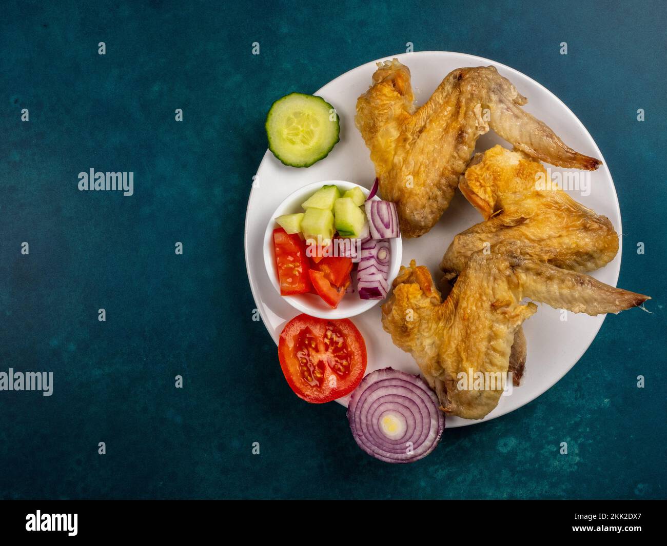 tres alitas de pollo cuenco de ensalada de acompañamiento en un plato  blanco sobre fondo turquesa Fotografía de stock - Alamy